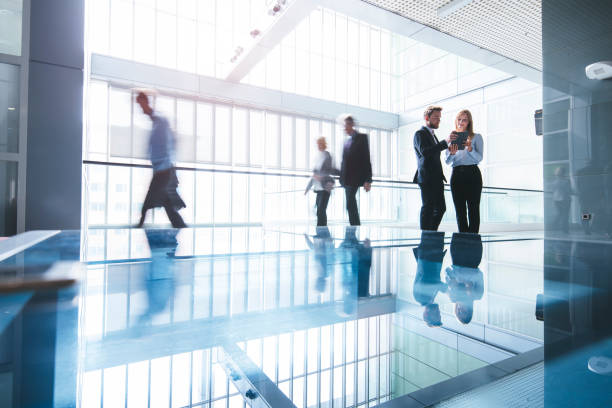 Heading to another successful business day Business people walking. Business man and business woman are standing in front, Holding digital tablet and discussing. Blurred motion. defocused woman stock pictures, royalty-free photos & images