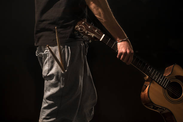 istock young man with acoustic guitar on black background 658273768