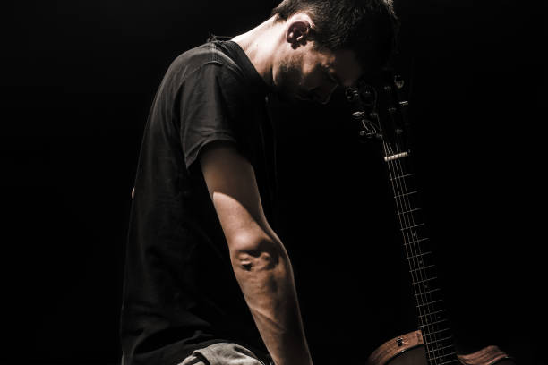istock young man with acoustic guitar on black background 658273796
