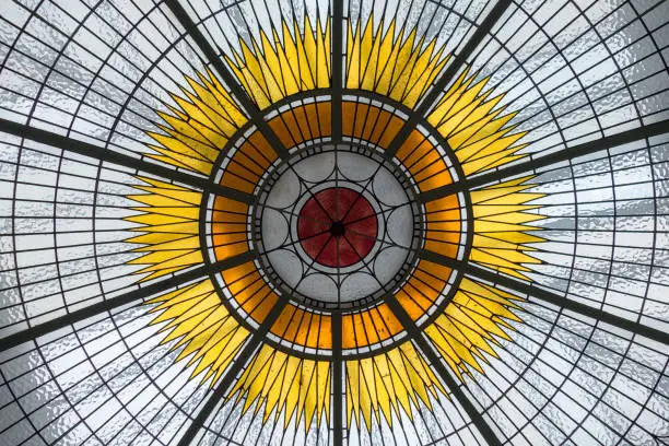 Detail of stained glass ceiling with solar centre and rays emanating in hub and spoke pattern