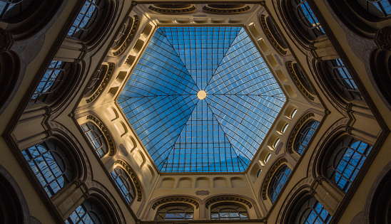 Hexagonal lead glass skylight ceiling in multi-storey atrium overlooked by windows around perimeter.