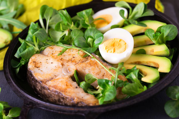 Grilled sheatfish fish steak with avocado, arugula and salad Grilled sheatfish fish steak with avocado, boiled egg, arugula and corn salad. Diet and healthy food. Selective focus, top view sheatfish stock pictures, royalty-free photos & images