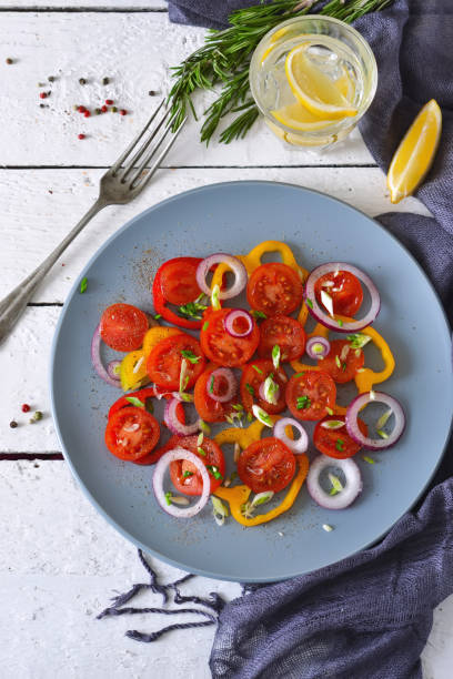 istock Salad with tomatoes, pepper and red onion with sauce on a gray plate on a white background. 658287274