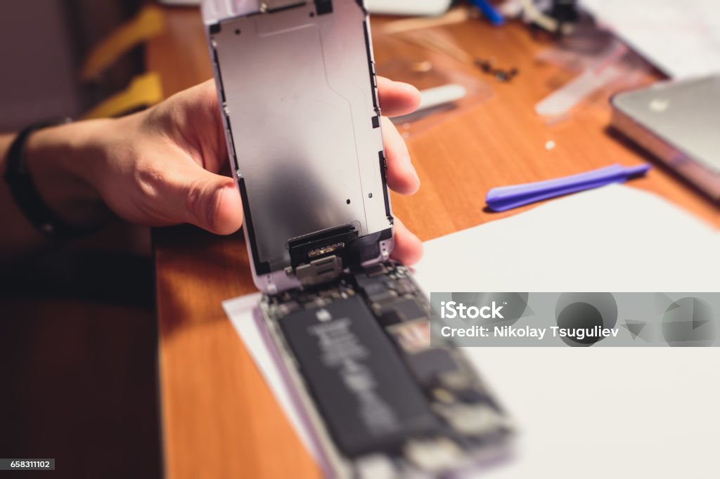 A close-up process of disassemble and dismantle modern mobile phone smartphone with broken shattered display glass and changing details at home Assistance Stock Photo A close-up process of disassemble and dismantle modern mobile phone smartphone with broken shattered display glass and changing details at home Assistance Stock Photo
