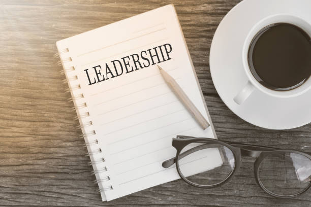istock Concept leadership message on notebook with glasses, pencil and coffee cup on wooden table. 658315688