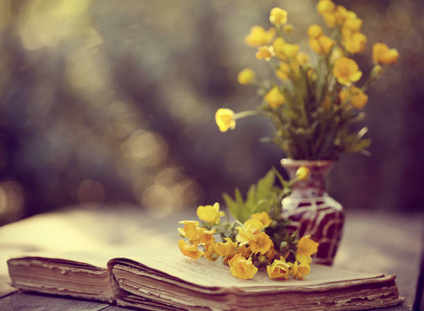 Bouquet of buttercups and the old open book on a table.