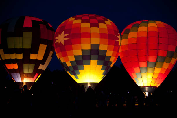 Hot air balloons lit up in the predawn sky