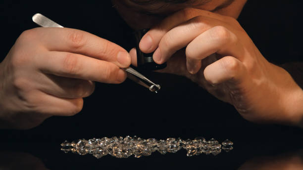 les pierres précieuses d'évaluateur regardent le diamant et les cristaux sur la table - diamond jeweller jewelry examining photos et images de collection