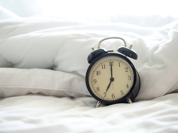 istock Alarm clock on bed in morning with sun light 658358272