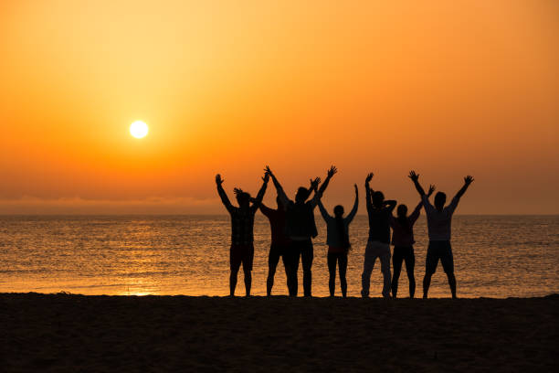istock Group of people excercising at dawn on beach 658359236