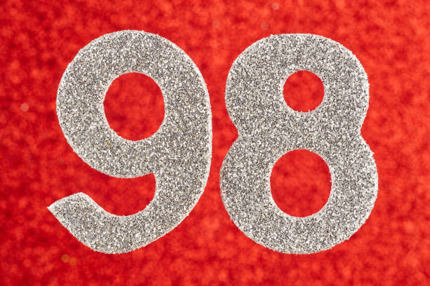 istock Number ninety-eight silver color over a red background. Anniversary. 658376118