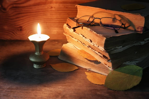 istock old tattered book on a wooden table lighted candle and glasses 658376802