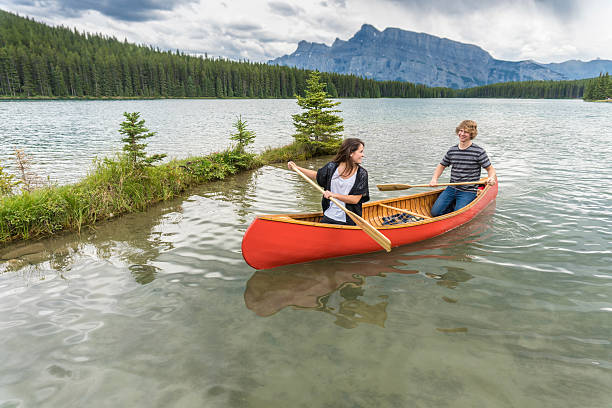 istock Young couple paddle canoe on mountain lake 658381107