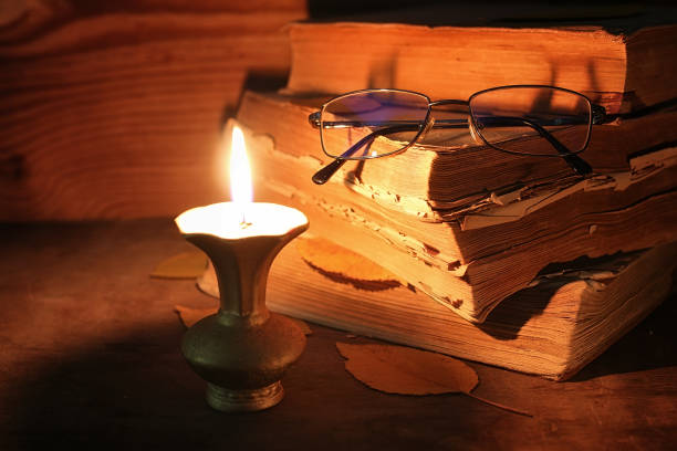 istock old tattered book on a wooden table lighted candle and glasses 658381304