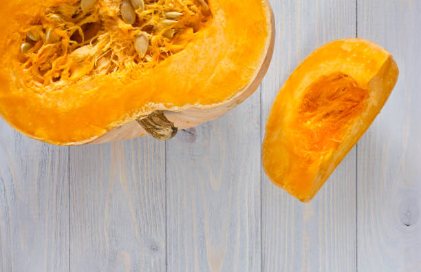 istock Pumpkin cut in half and piece on blue wooden background. 658382332