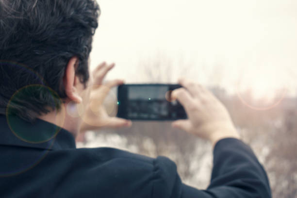 Kharkiv, Ukraine - October 14, 2019: Men on street photographing with mobile phone, background is blured city