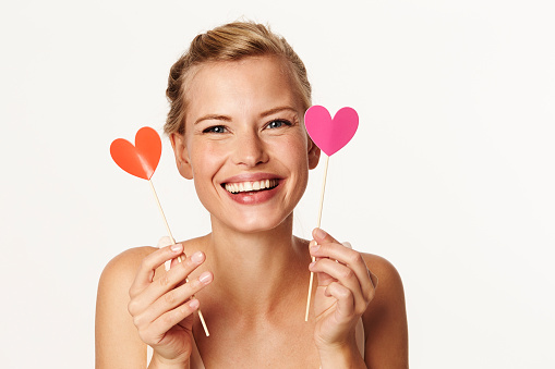 Beautiful woman holding heart shapes in studio