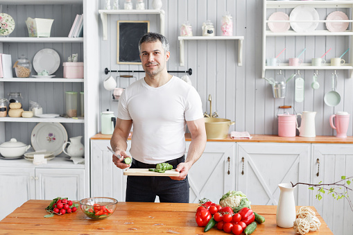 Middle-aged athlete, holding a bowl of a plate with a prepared salad of cucumber and tomato