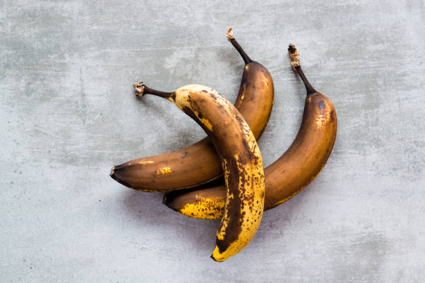 Brown bananas on a concrete table Three rotten brown bananas on a concrete table ripe stock pictures, royalty-free photos & images