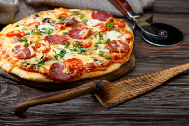 istock Homemade pizza on a rustic table. Wooden pizza server. 658413222