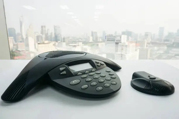 close up IP conference phone with wireless speaker on table for meeting