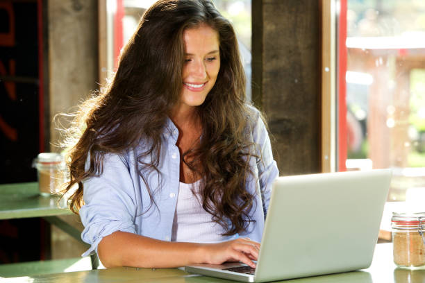 istock smiling young woman working on laptop at cafe 658430910