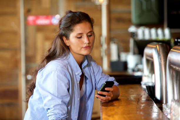 istock young woman at the bar using mobile phone 658430964
