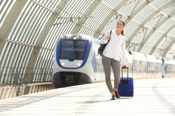 istock happy woman walking with suitcase at train station 658431038