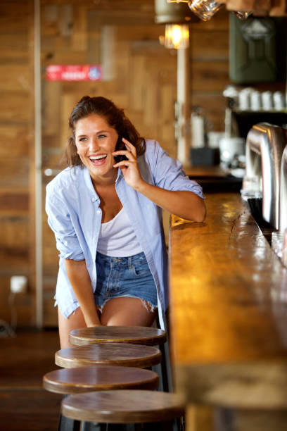 istock young woman at the bar talking on mobile laughing 658431146