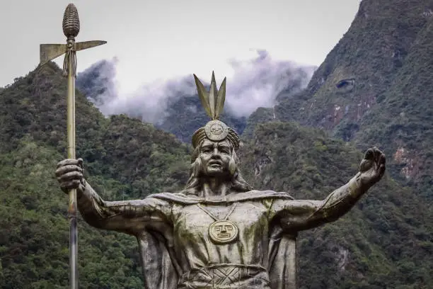 Photo of Statue of Pachacuti, an Inca leader, background mountains and clouds, in Aguas Calientes, starting point to Machu Picchu