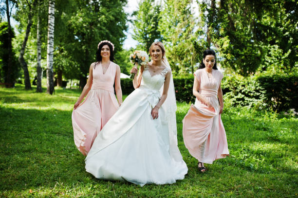 istock Bride posed on park with two cute brunette bridesmaids on pink dresses. 658446738