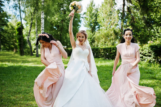 istock Bride posed on park with two cute brunette bridesmaids on pink dresses. 658446876