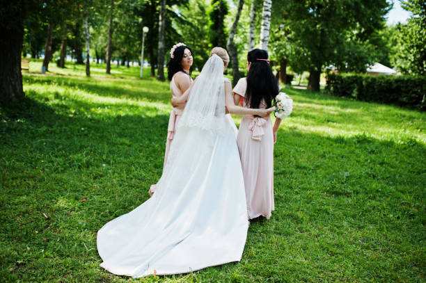 istock Bride posed on park with two cute brunette bridesmaids on pink dresses. 658446894