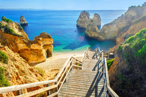 деревянный пешеходный мост к красивому пляжу прайя-да-камило возле лагоса - portugal стоковые фото и изображения