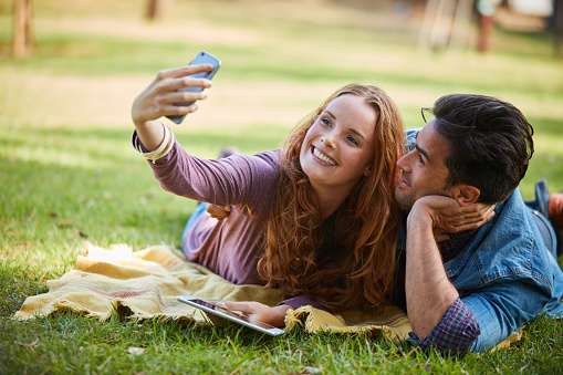 Portrait of a young couple taking a selfie while out at the park