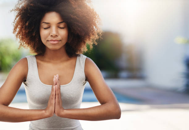 Balancing mind and body Cropped shot of a sporty young woman practicing yoga outdoors the black womens expo stock pictures, royalty-free photos & images