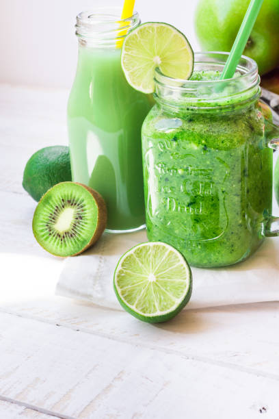 istock Mason jar mug with fresh vegetable smoothie, bottle with green fruit juice, ingredients apples, citrus, kiwi on kitchen table outdoors 658452562