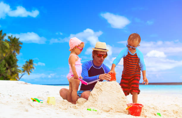 istock father with son and daughter building castle on beach 658455064