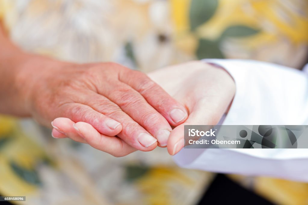 Elderly aid Young doctor holds the elderly woman hands A Helping Hand Stock Photo