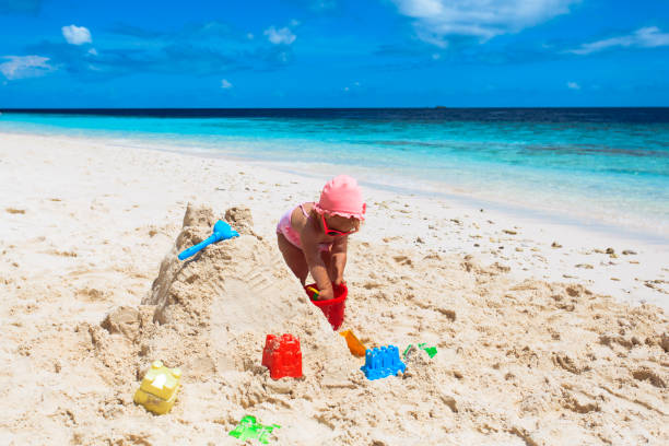istock cute little girl play with sand on beach 658459366