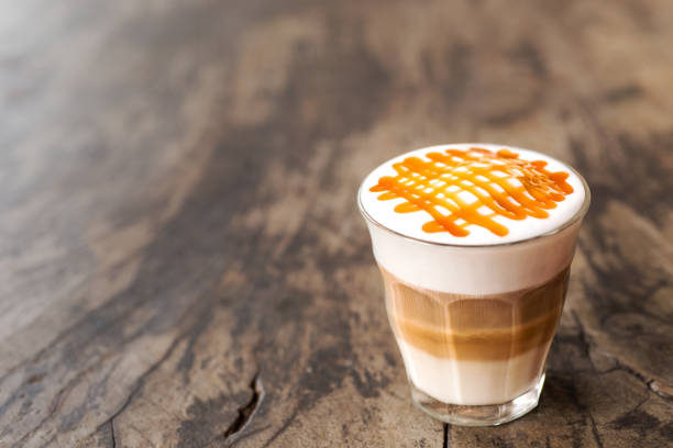 hot caramel macchiato coffee glass of hot caramel macchiato coffee on wooden table in coffee shop macchiato stock pictures, royalty-free photos & images