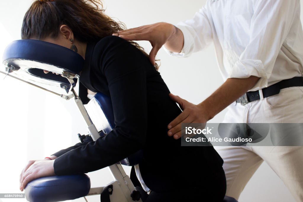 business woman receiving shiatsu on a quick massage chair business woman receiving shiatsu in her office sitting on a quick massage chair Massaging Stock Photo