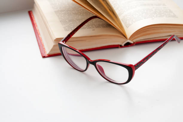 istock On the open book glasses lie on a light background 658477376