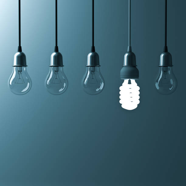 istock One hanging energy saving light bulb glowing different stand out from unlit incandescent bulbs with reflection on dark cyan background , leadership and different creative idea concept. 3D render 658483388