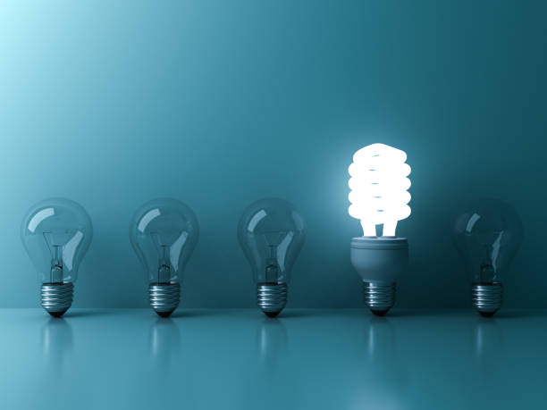 istock Eco energy saving light bulb , one glowing fluorescent lightbulb standing out from unlit incandescent bulbs reflection on blue background , individuality and different ideas concepts 658483422
