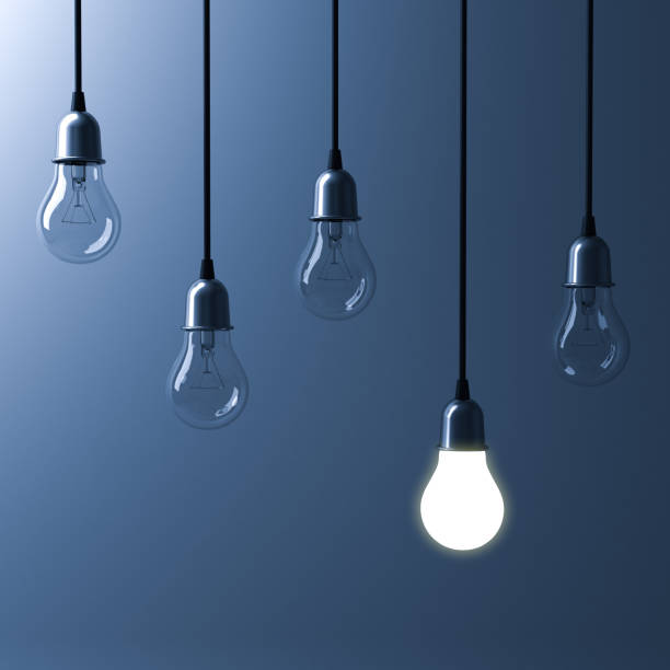 istock One hanging light bulb glowing different and standing out from unlit incandescent bulbs with reflection on dark blue background , leadership and different business creative idea concept. 3D render 658483652