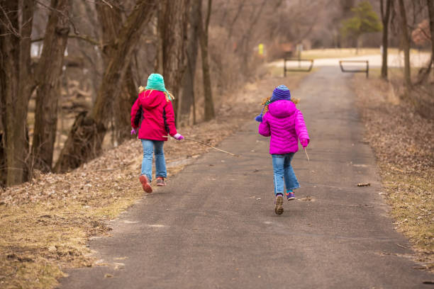 istock Two Girls Running Down Park Trail in Early Springtime 658484436