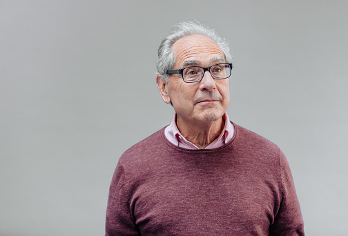 Portrait of a surprised expressive face and happy senior French businessman with glasses and smart casual, real people studio shot with copy space on gray background. XXXL