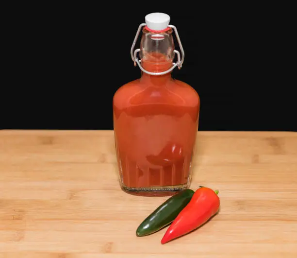 Still life arrangement of hot sauce in a preserving bottle.