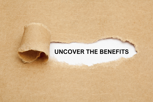 Text Uncover The Benefits appearing behind ripped brown paper.